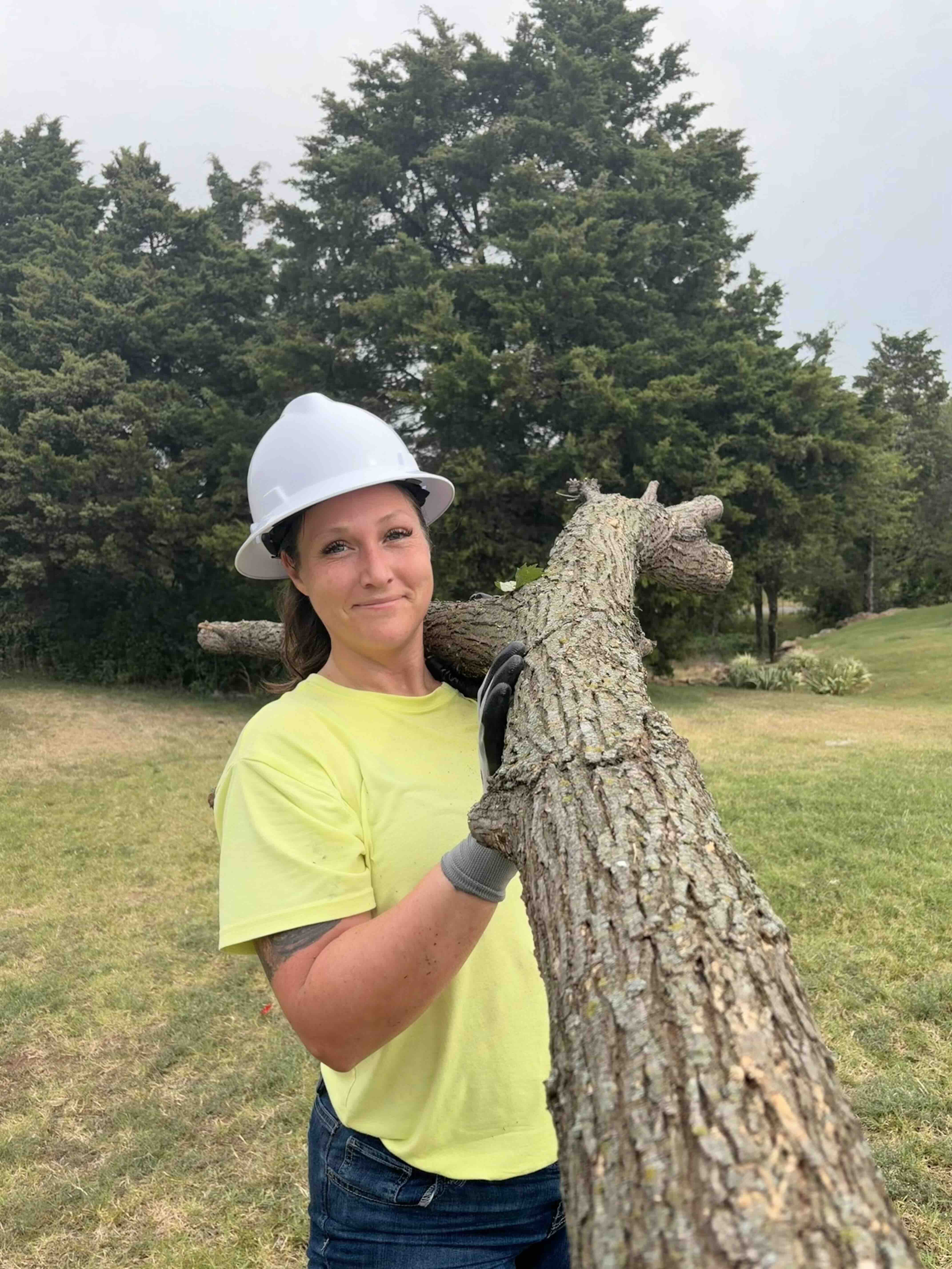 Christina Castillo carrying a tree limb during tree work in Edmond, Oklahoma